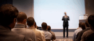 person speaking on stage to group
