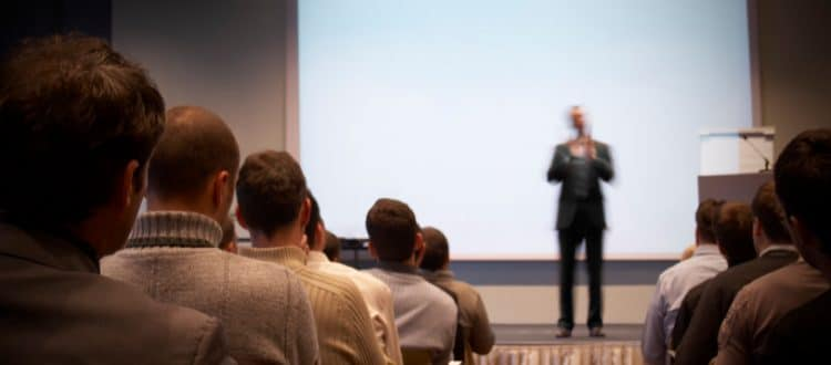 person speaking on stage to group