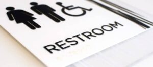 A close-up of a bathroom sign featuring bold, sans serif ada complaint fonts that are easy to read and tactile for visually impaired individuals.