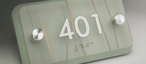 Close-up of an ADA-compliant sign crafted from routing Novacryl photopolymer, featuring crisp edges, tactile text, and a polished finish on a durable PETG base.