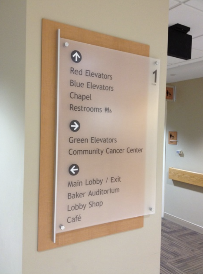 Hospital lobby wayfinding signage designed with wood laminate and Novacryl LP photopolymer for easy navigation.