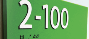 The benefits of ADA braille photopolymer signs, including durability and accessibility, are shown with a braille sign.