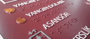 Close-up of a sign displaying braille and raised text, meeting ADA compliance codes.
