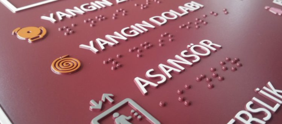 Close-up of a sign displaying braille and raised text, meeting ADA compliance codes.