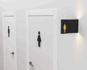 A restroom sign with tactile symbols and raised braille text, providing accessibility for visually impaired individuals. The photopolymer material used in this sign complies with Proposition 65 regulations.