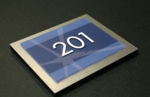 ADA compliant sign featuring raised tactile letters and braille.