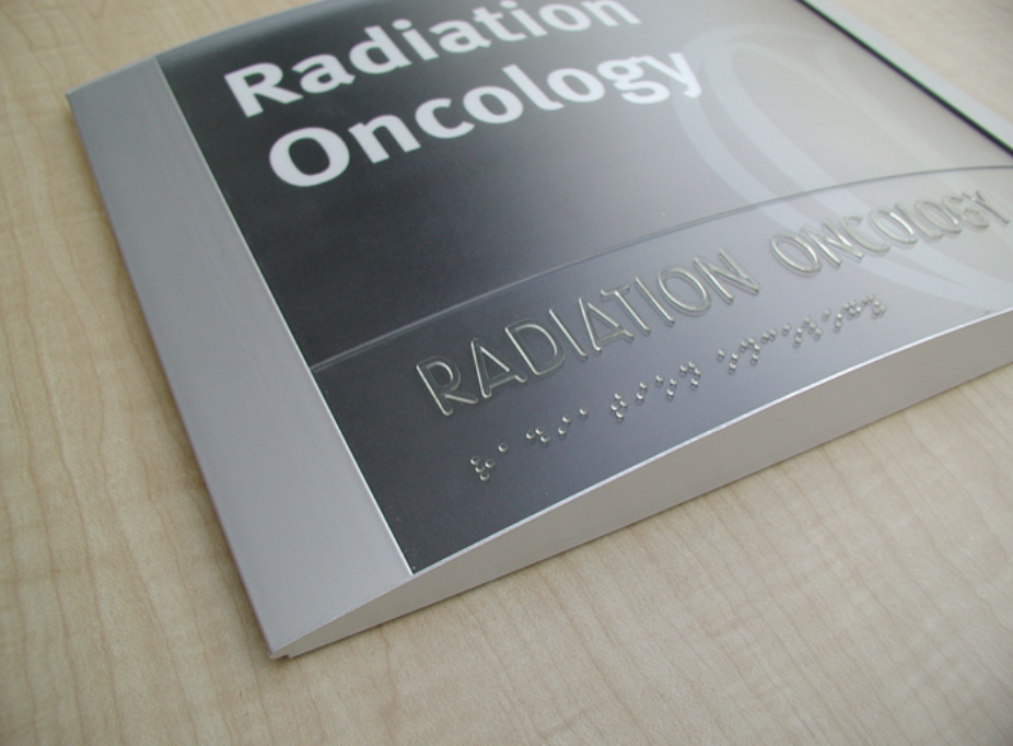 Close-up of an ADA compliant sign with clear, easy-to-read text and braille.