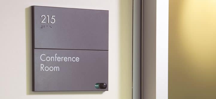 A conference room sign mounted properly according to ADA signage height standards.