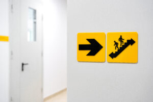 Accessible exit sign requirements include raised tactile lettering and braille, and proper mounting height on a wall in a public building.