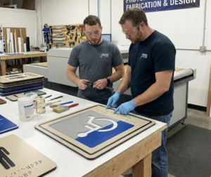 Two men working together on ADA sign fabrication.